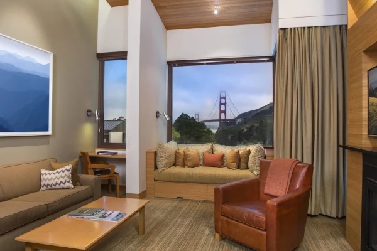 Hotel guest suite living area with leather armchair, sofa and a picture window framing the Golden Gate Bridge