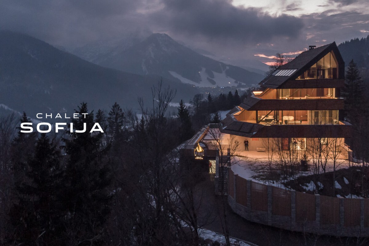 Chalet Sofija exterior at dusk, modern wooden chalet glowing against mountain backdrop