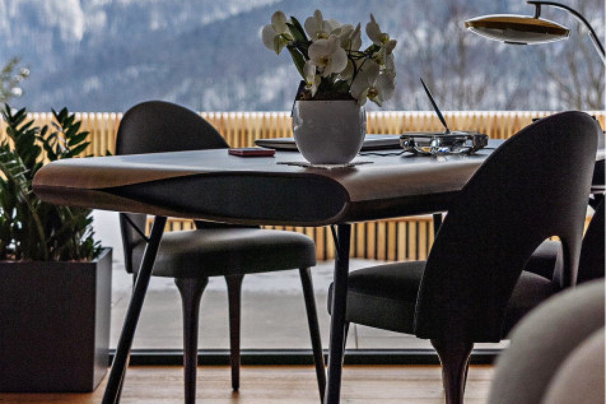 Interior table setting by window with mountain view, orchid centerpiece and dark chairs