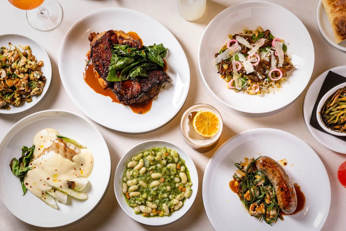 Overhead view of a laid table at Chambers with multiple shared plates: roast chicken, sausage, beans, mushroom dish, and drinks.