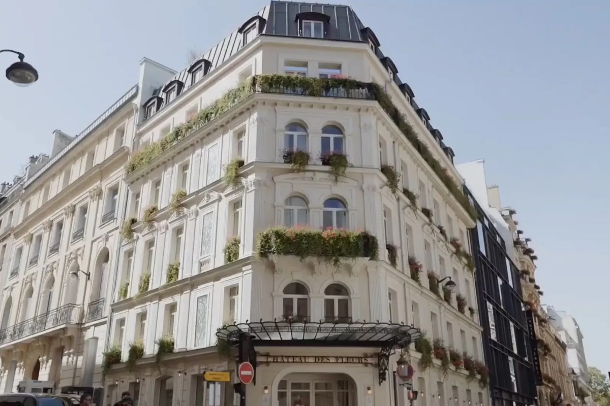 Full view of Château des Fleurs hotel facade on a Paris street corner with flower-filled balconies