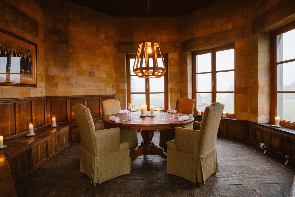 Round dining table set in a stone tower turret room with candlelight and garden views