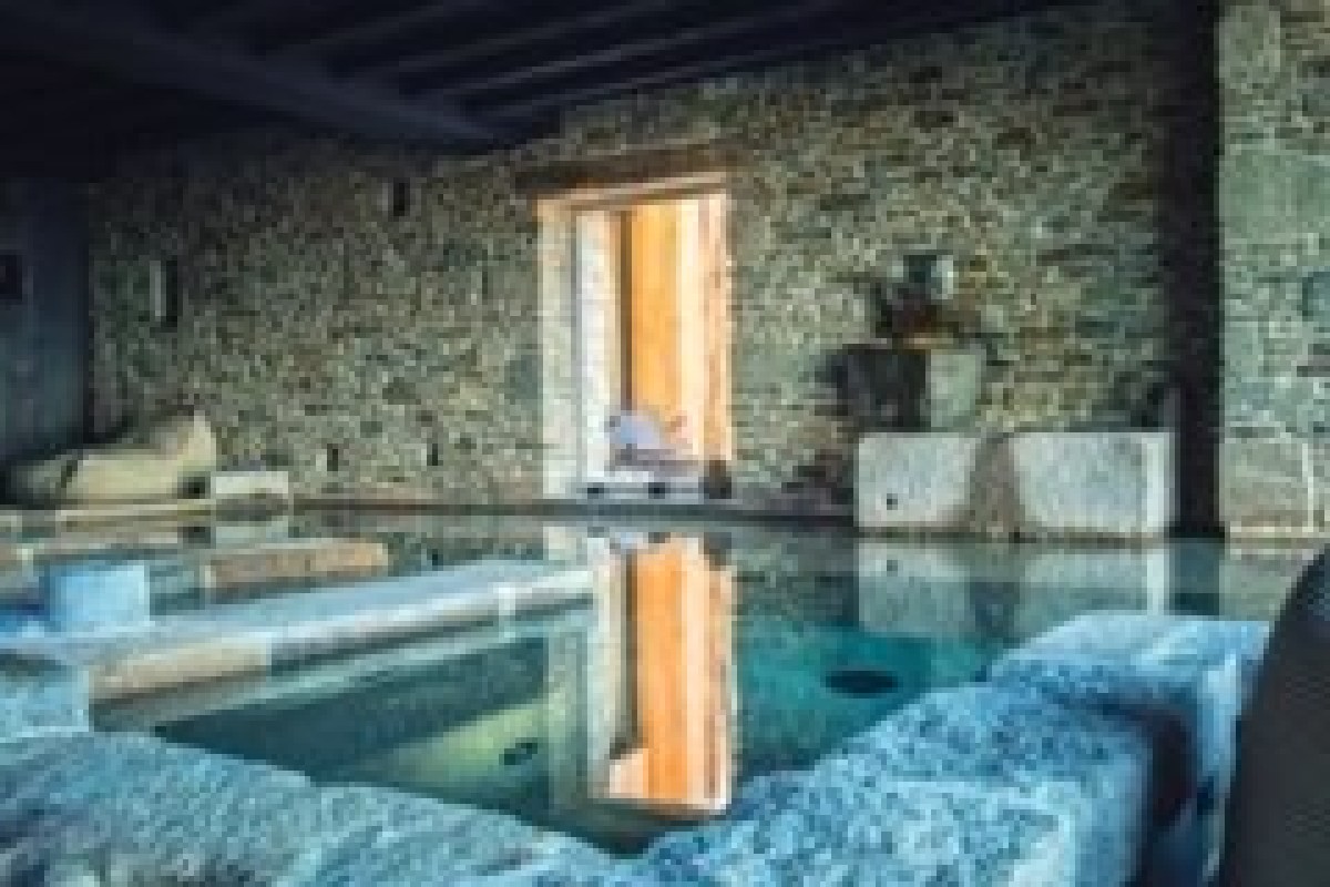 Indoor stone-walled spa pool with warm lighting and loungers at the hotel