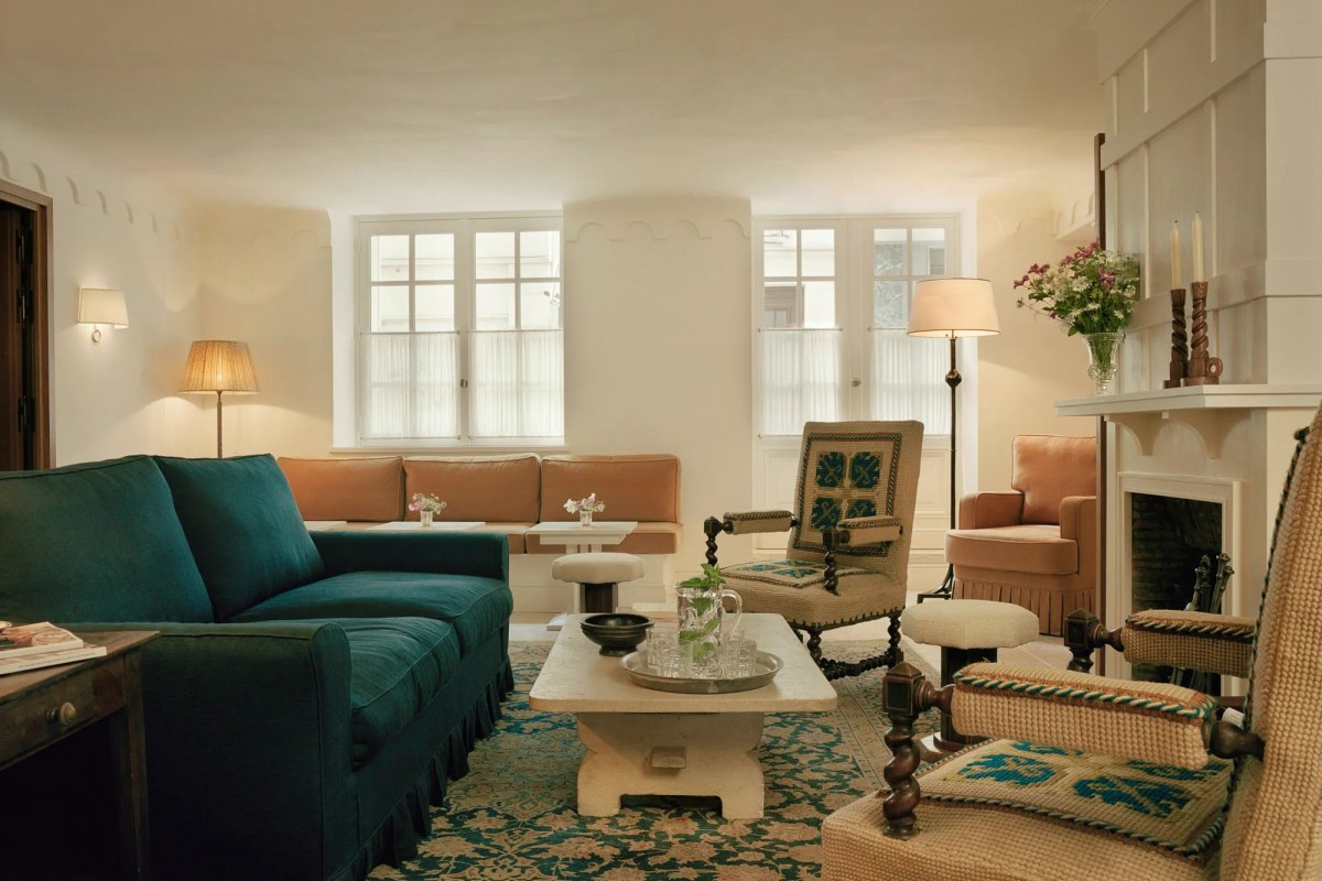 Hotel lounge with teal sofa, patterned chairs, coffee table and fireplace