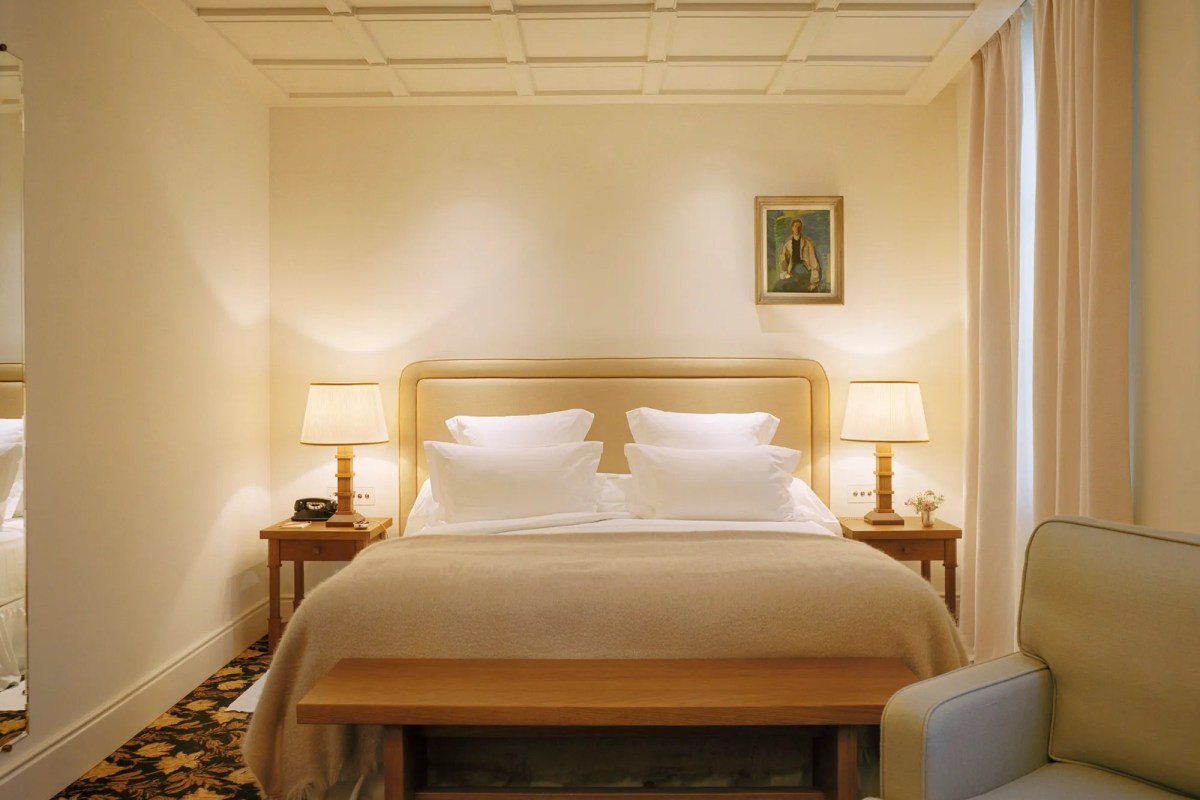 Guest room with bed, bedside lamps, painting above headboard and armchair