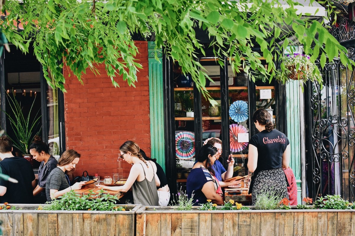 Exterior terrace of Chavela's with diners seated under greenery, visible signage