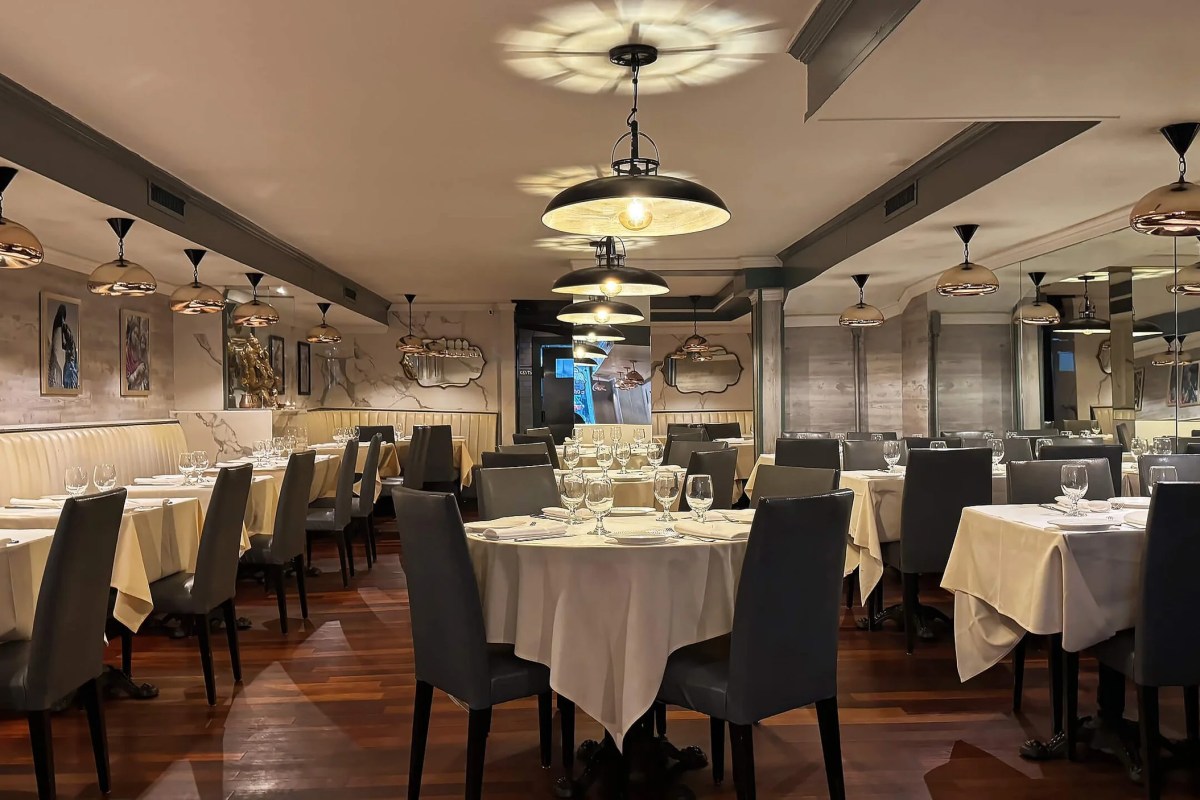 Elegant dining room with round tables set in white linen and modern pendant lighting