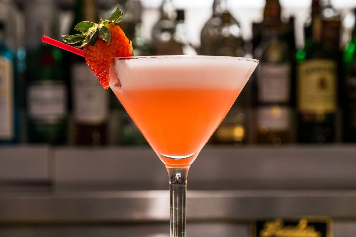Pink cocktail with strawberry garnish in a martini glass at the bar