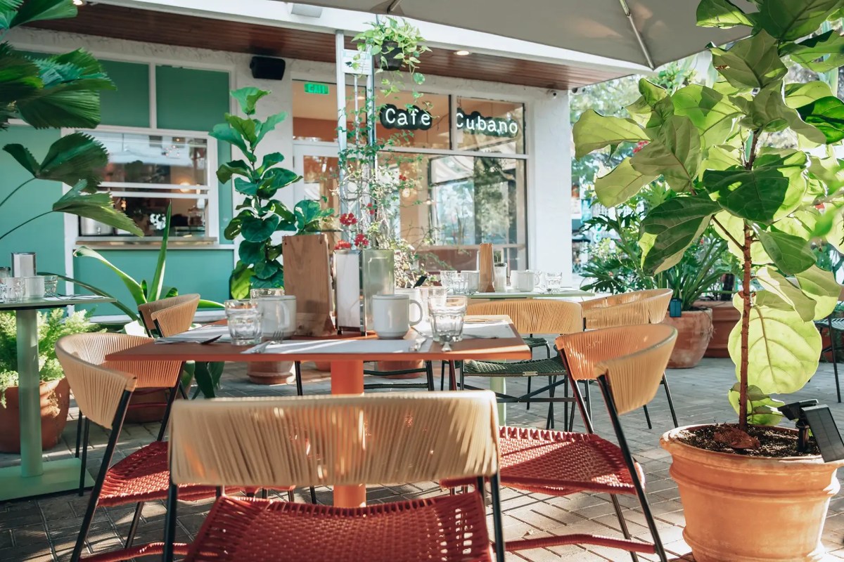 Outdoor terrace dining area at Chug's Diner with teal exterior, plants, and Cafe Cubano sign