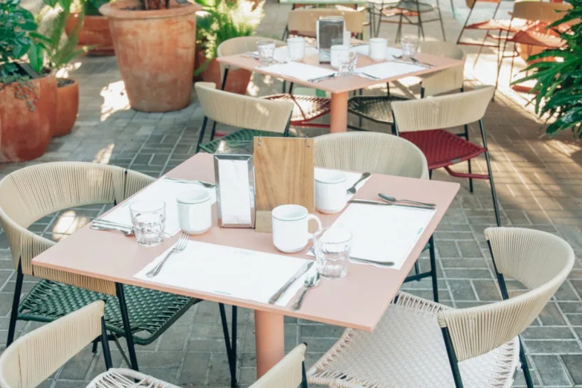 Set tables on the outdoor terrace with place settings and woven chairs