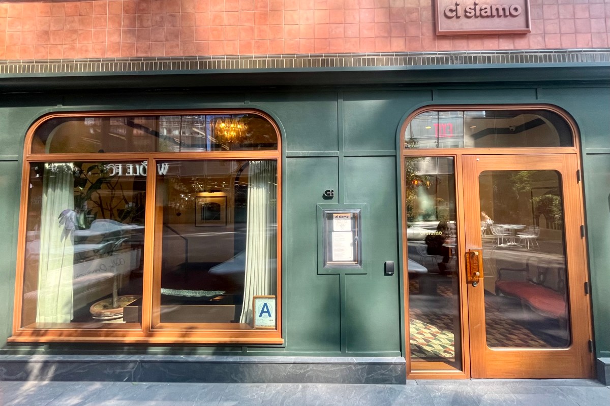 Exterior storefront of Ci Siamo restaurant in NYC, green facade with wooden door and arched window.