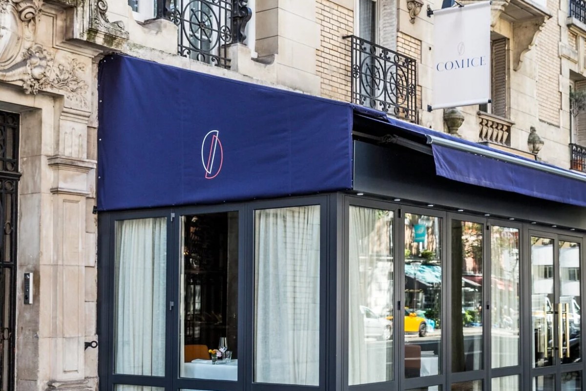 Comice restaurant exterior with blue awning and sign on a Parisian street