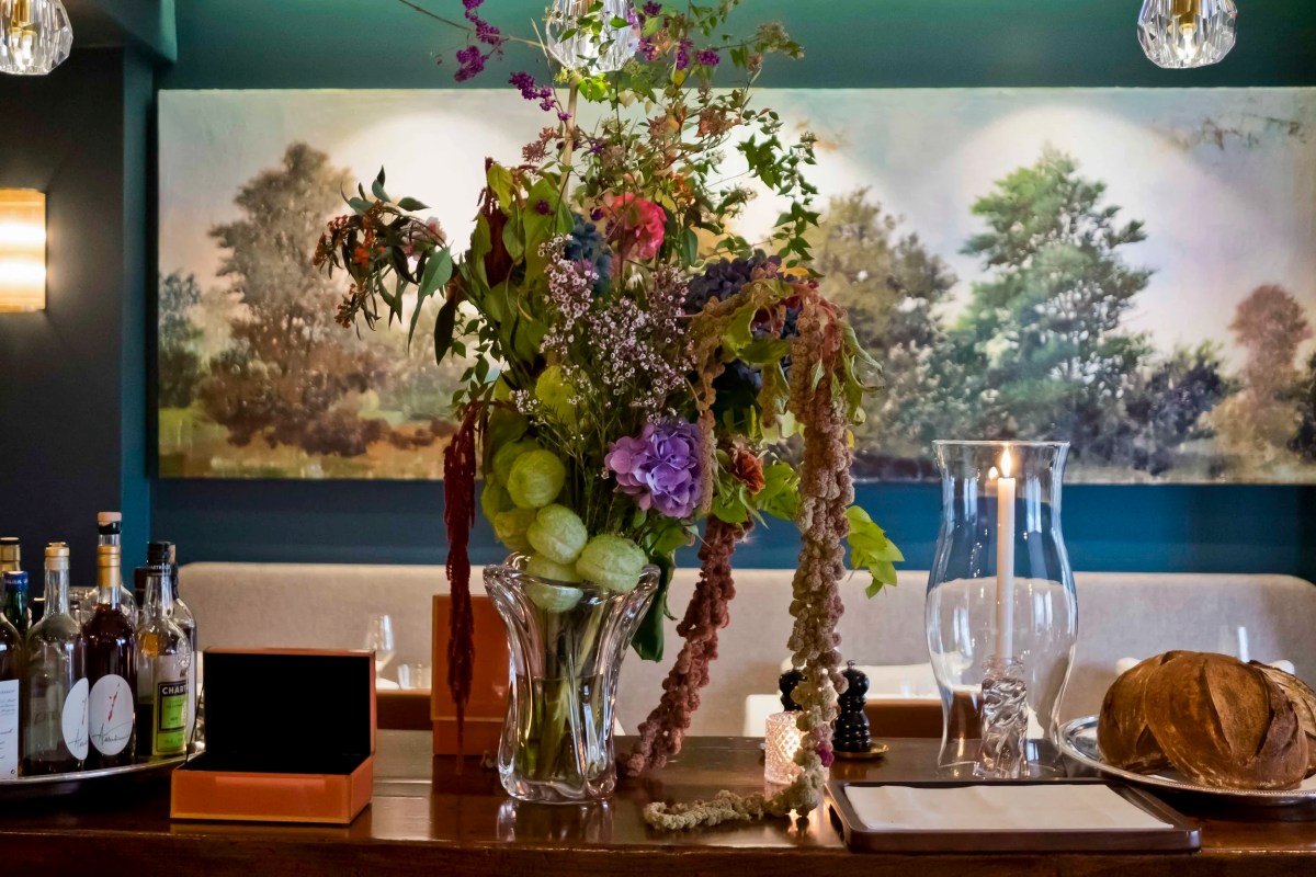 Elegant bar area with floral arrangement, candle, and mural in Comice's dining room