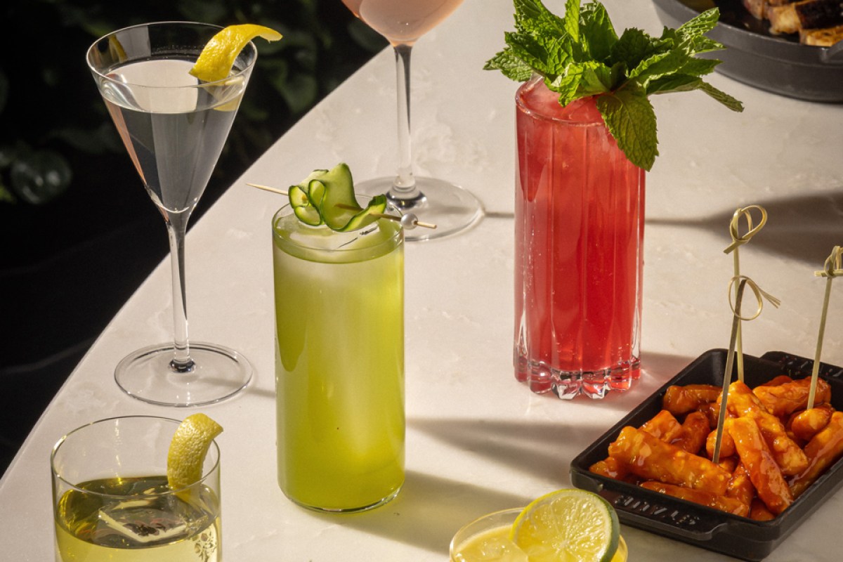 Colorful cocktails and a dish of glazed appetizers on a marble bar table