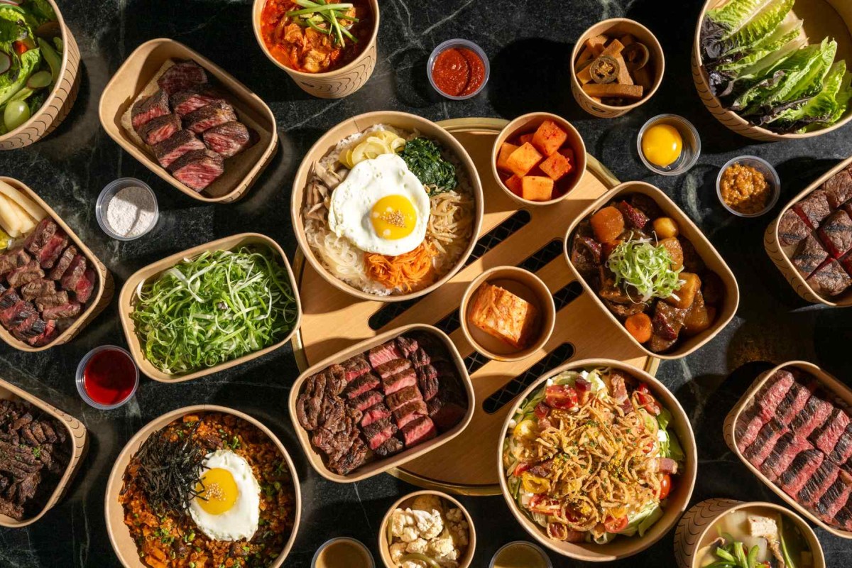Overhead view of assorted Korean steakhouse dishes including steak, bibimbap and banchan