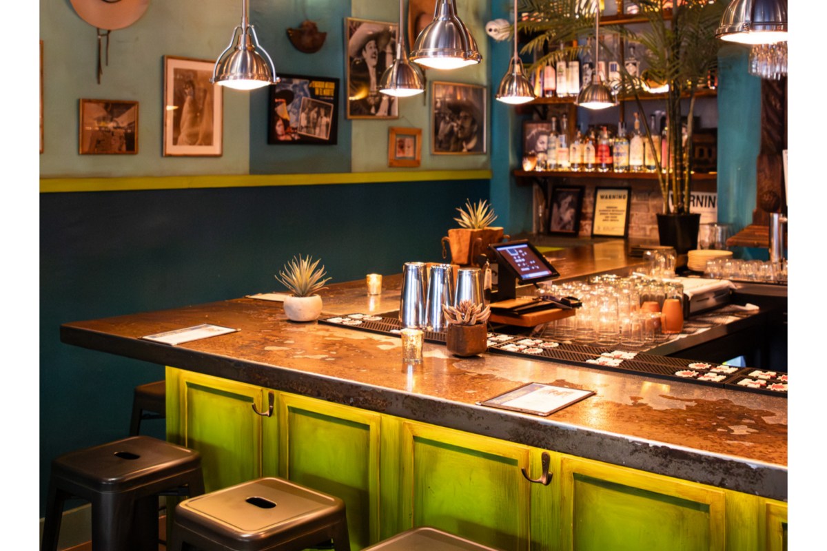 Restaurant bar counter with stools, bottles, and decorative wall photos