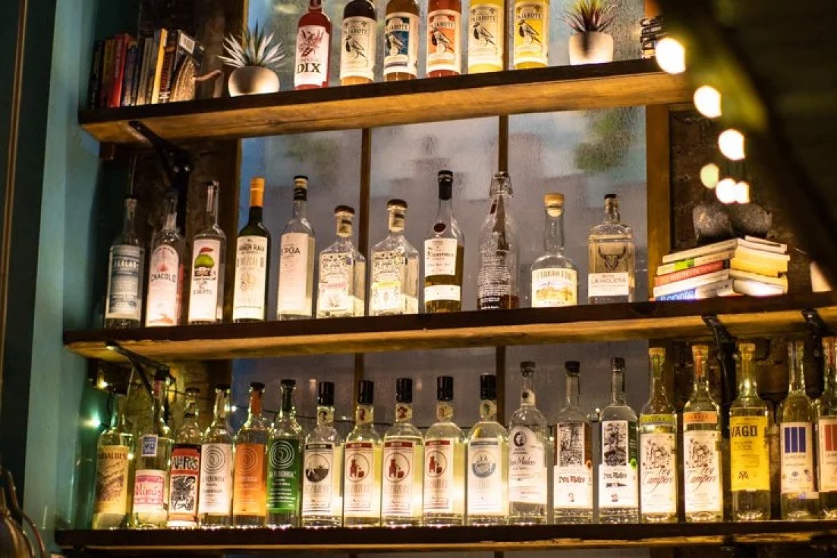Wooden shelves lined with various liquor bottles, tequila and mezcal