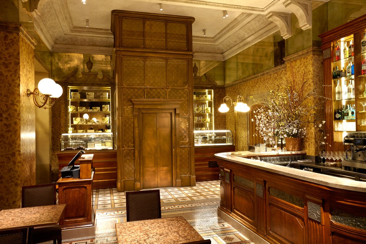 Ornate bar area with wood paneling, glass display cases, mosaic floor, and a flower arrangement.