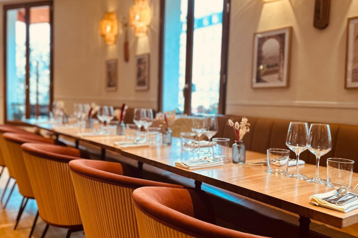 Elegant dining room with wood table, orange velvet chairs, wine glasses set for a meal, warm lighting.