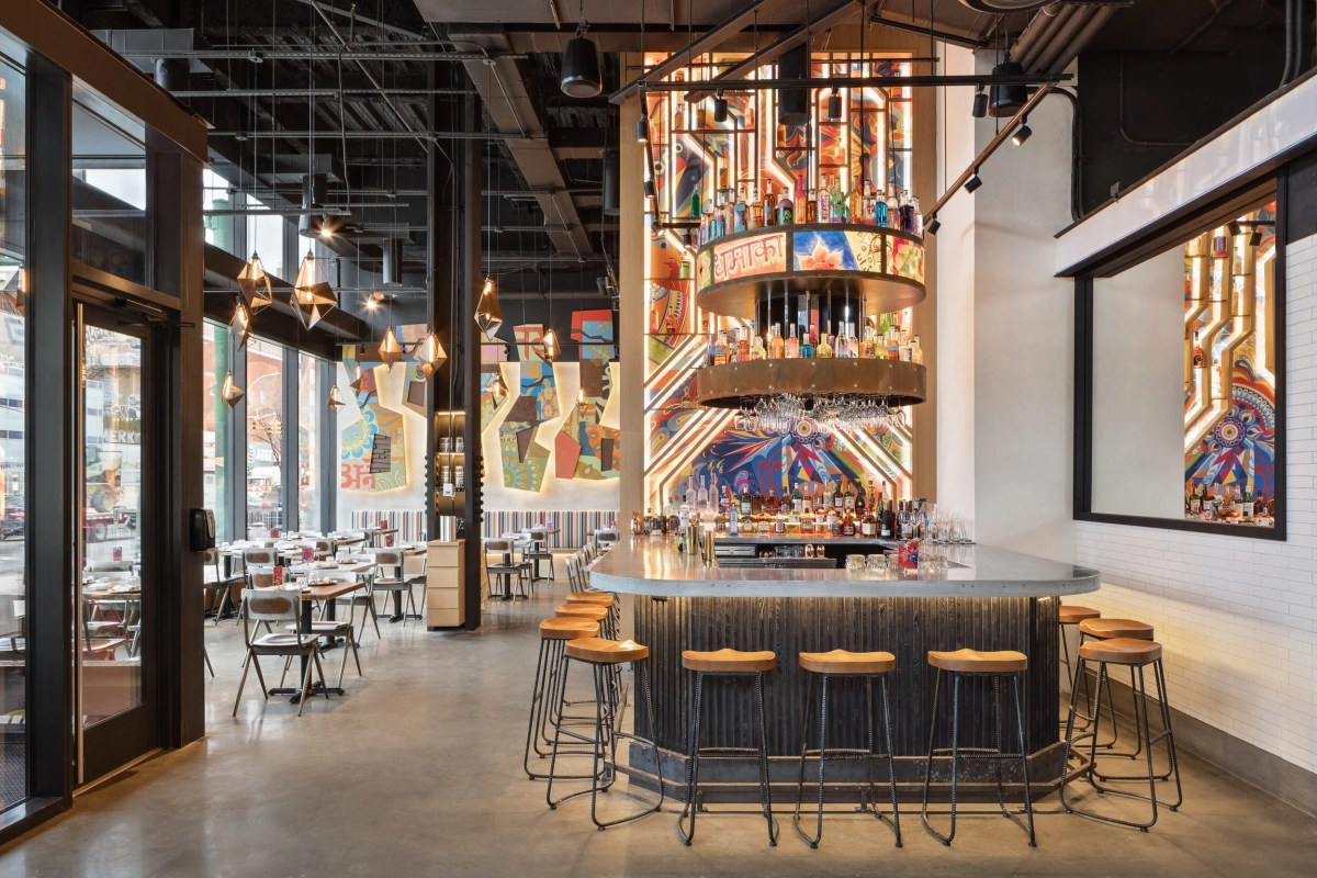 Interior view of Dhamaka with bar, colorful mural, and dining tables