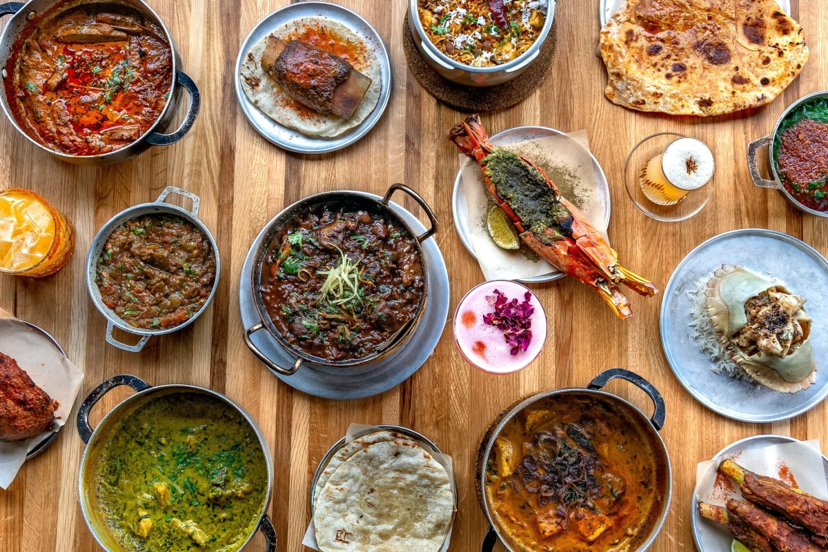Overhead view of multiple Indian dishes spread across a wooden table at Dhamaka