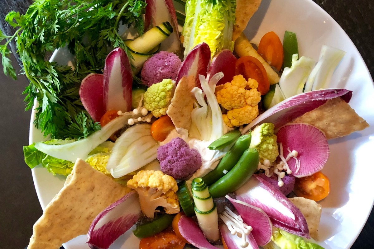Colorful vegetable salad plate with radishes, cauliflower, tomatoes, and crackers