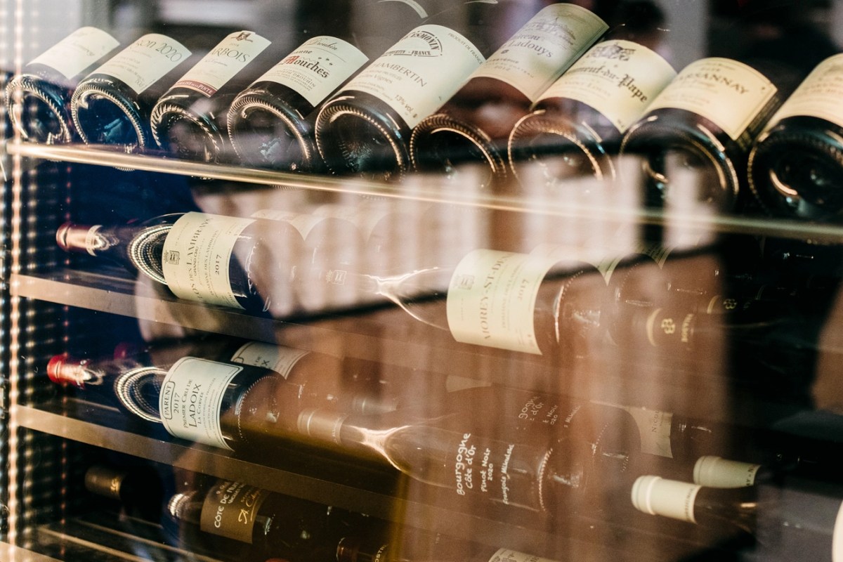 Close-up of wine bottles stored on shelves, labels visible, in a wine fridge or cellar