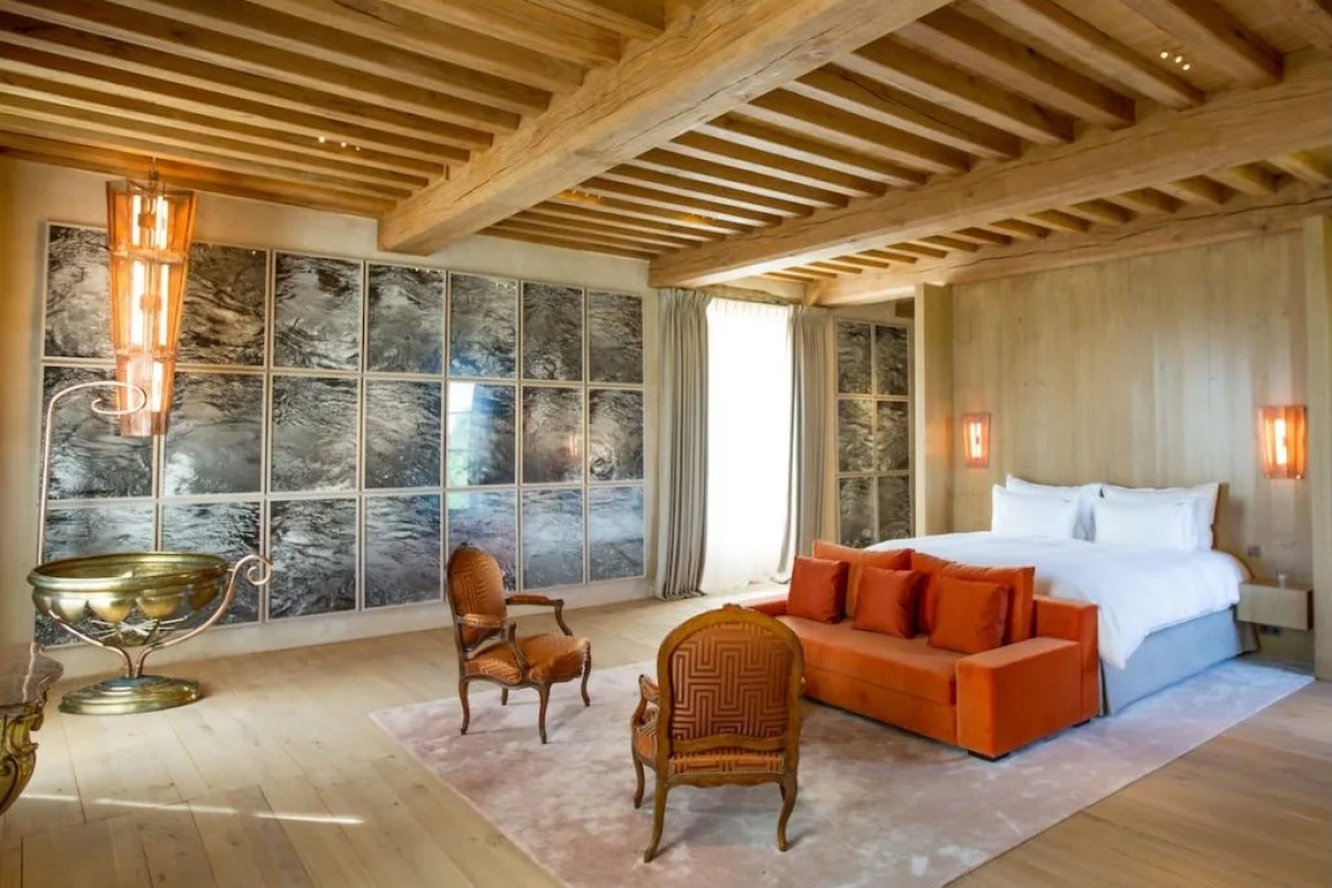 Modern suite with wood-beamed ceiling, orange sofa and reflective wall panels