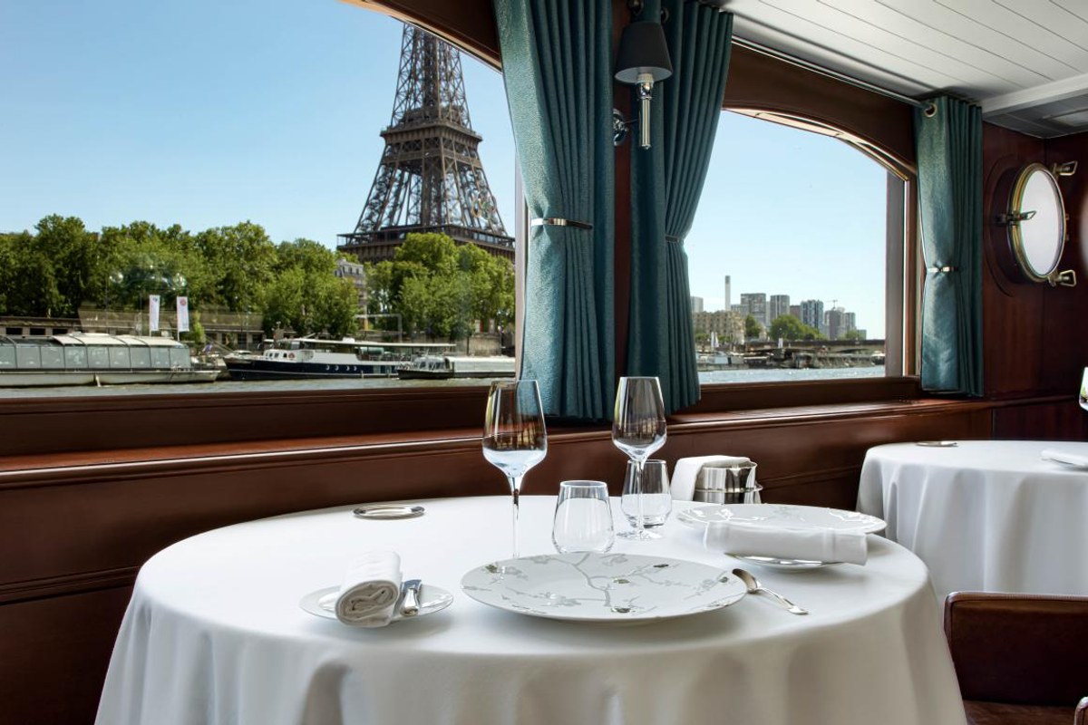 Table set with wine glasses and patterned plate, Eiffel Tower visible through window