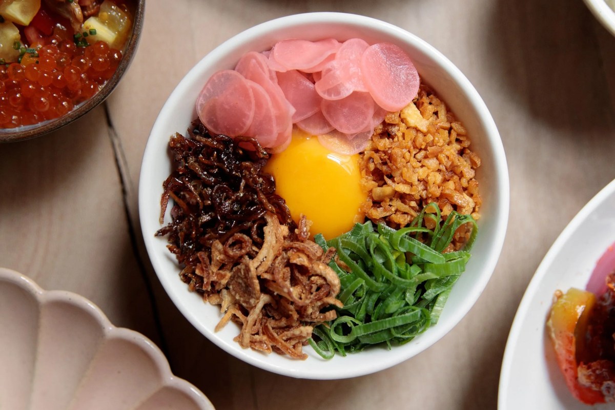 Overhead view of a bowl with raw egg yolk, pickled radish, fried shallots, and scallions, Double Dragon dish