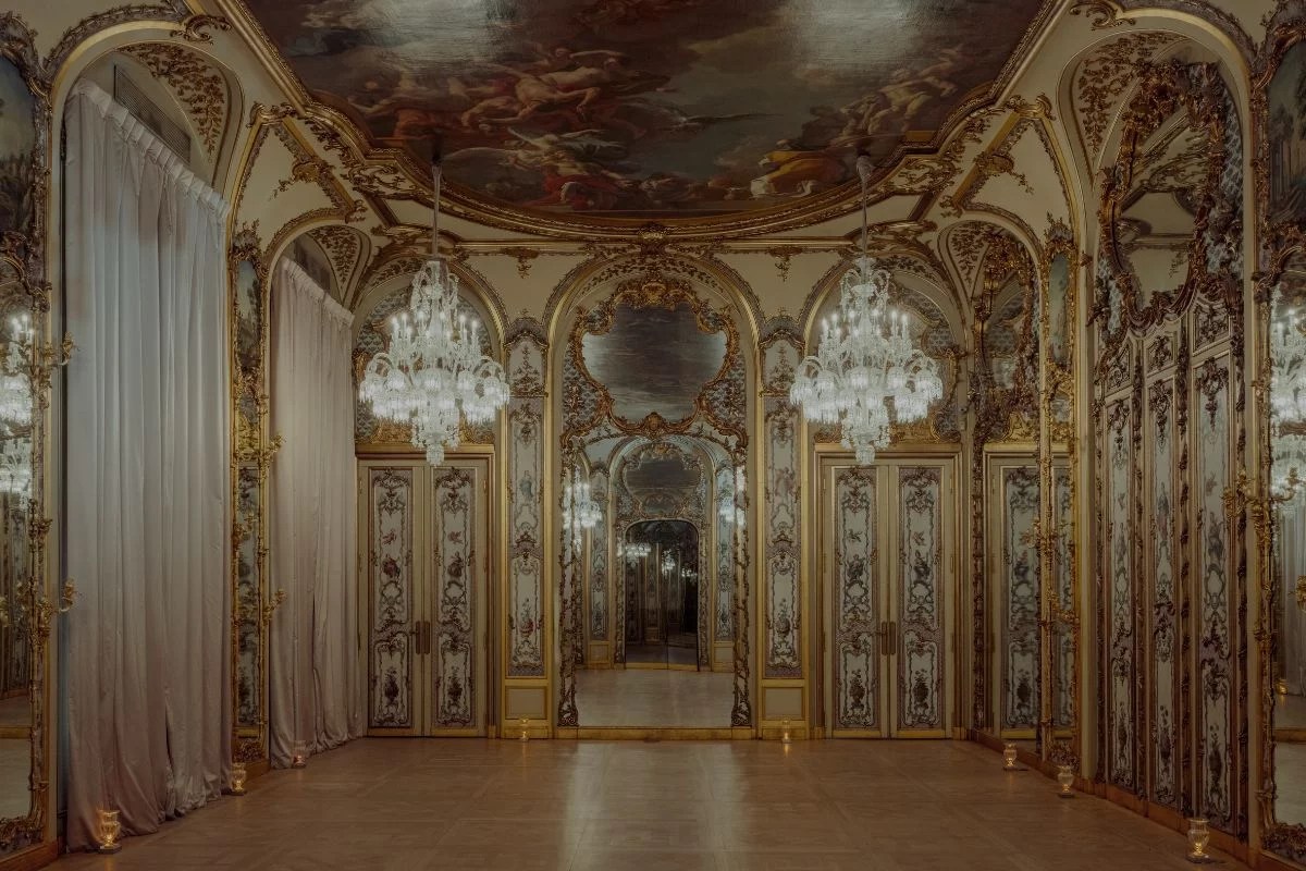 Grand gilded salon with crystal chandeliers, painted ceiling and mirrored arches, candlelit floor