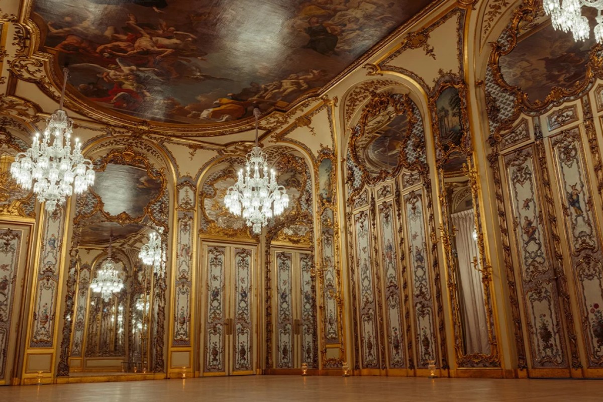 Opulent gilded dining hall with painted ceiling fresco, mirrored panels and crystal chandeliers