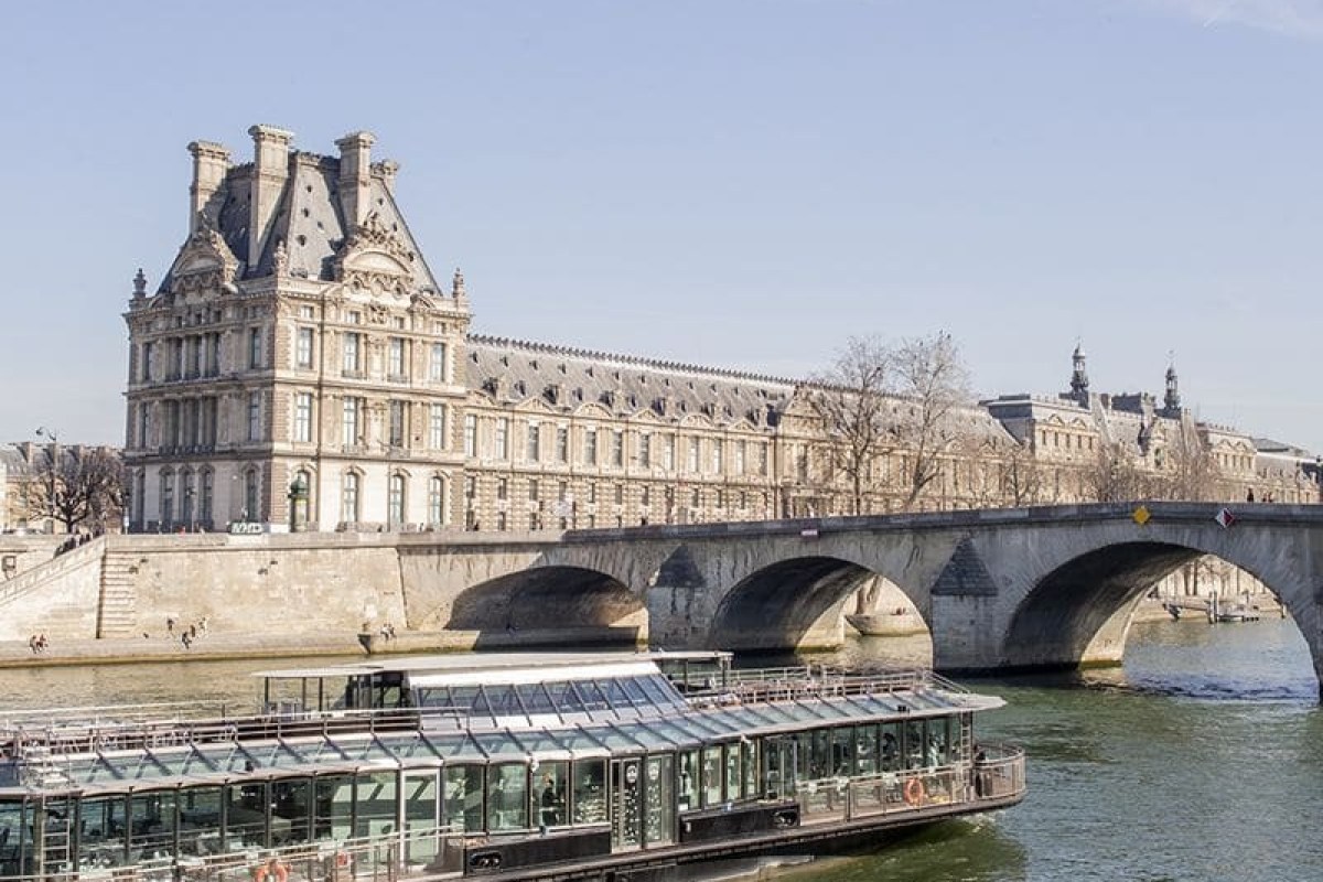 Ducasse sur Seine glass-roofed boat restaurant cruising past the Louvre on the Seine