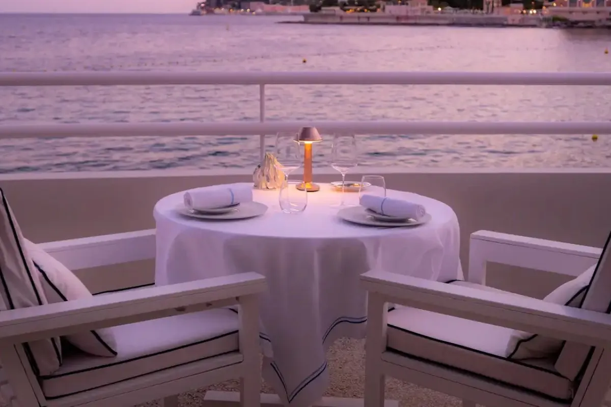Romantic candlelit terrace table for two overlooking the sea at dusk at Elsa Marcel Ravin