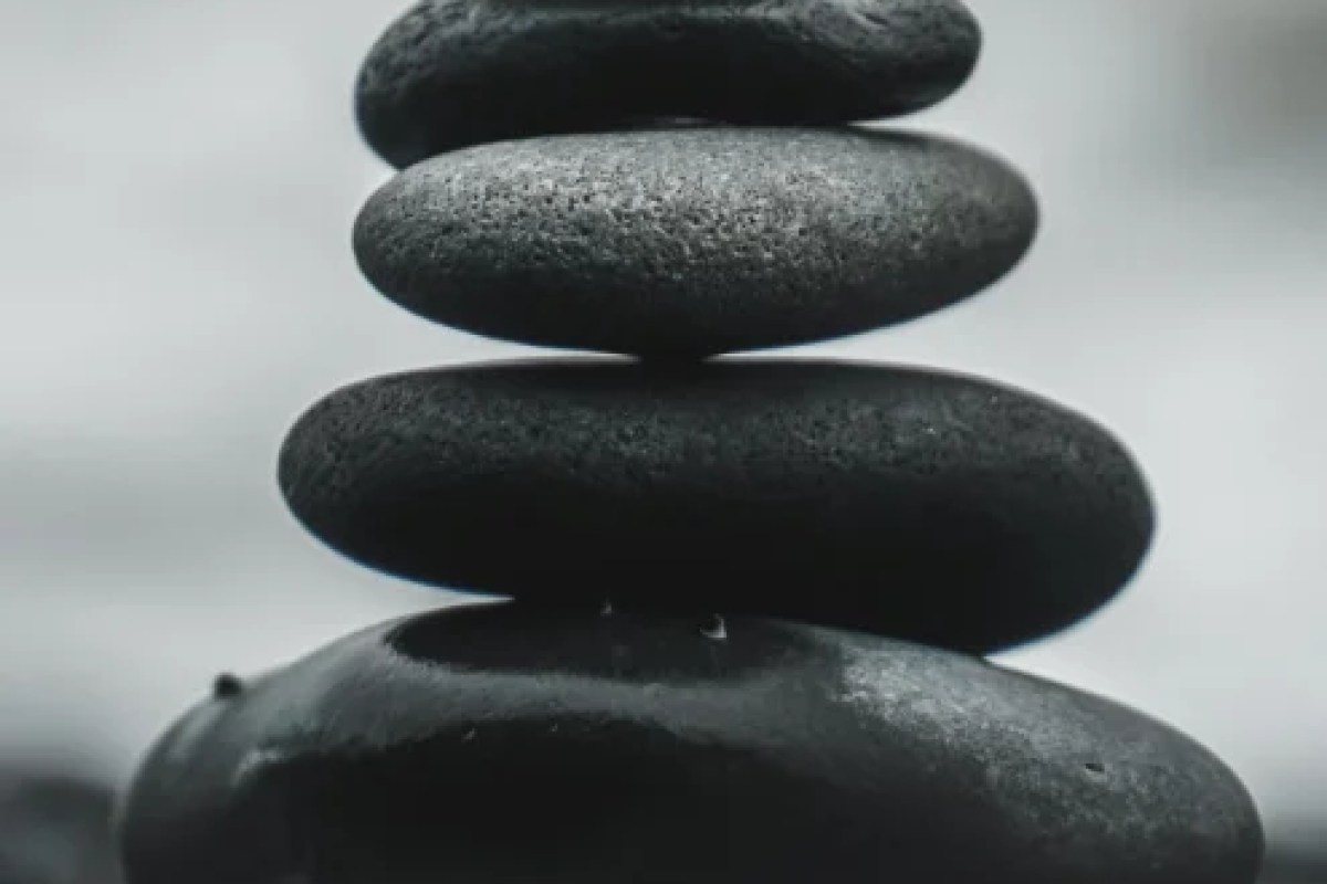 Stack of smooth black balancing stones, evoking a spa or wellness setting.