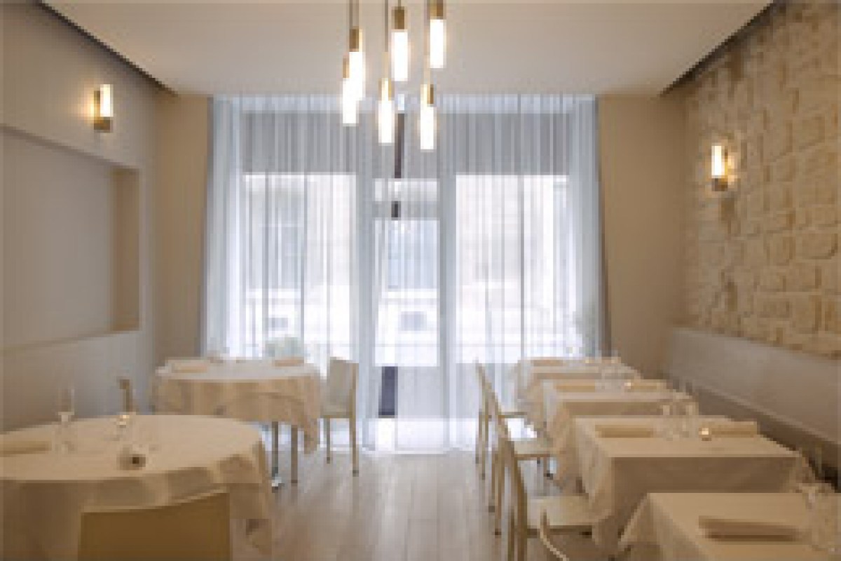 Bright dining room with white-clothed tables, stone wall accent and pendant lights