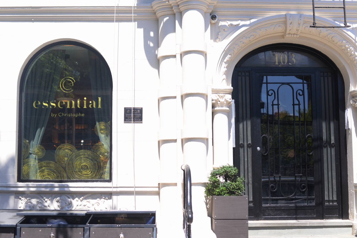 Exterior facade of Essential by Christophe with arched window, gold logo signage, black door at 103, and iron railings.