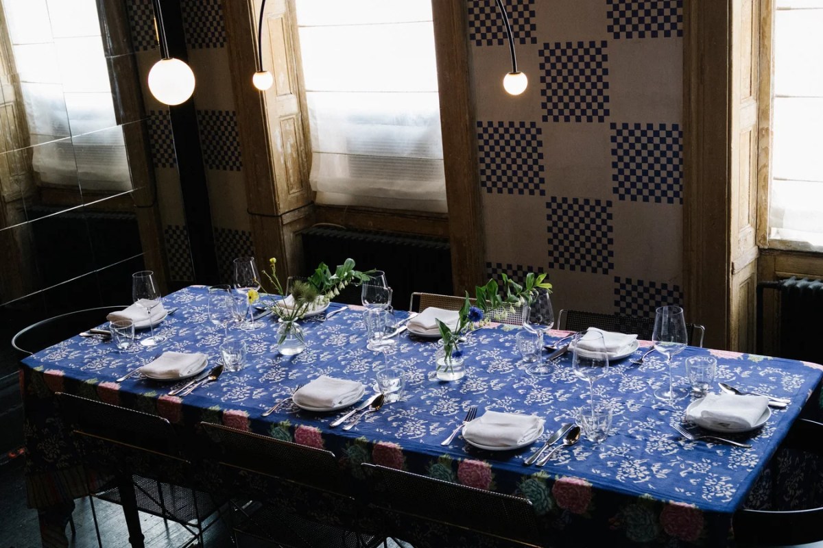 Set dining table with blue floral tablecloth, wine glasses, napkins, in a restaurant dining room