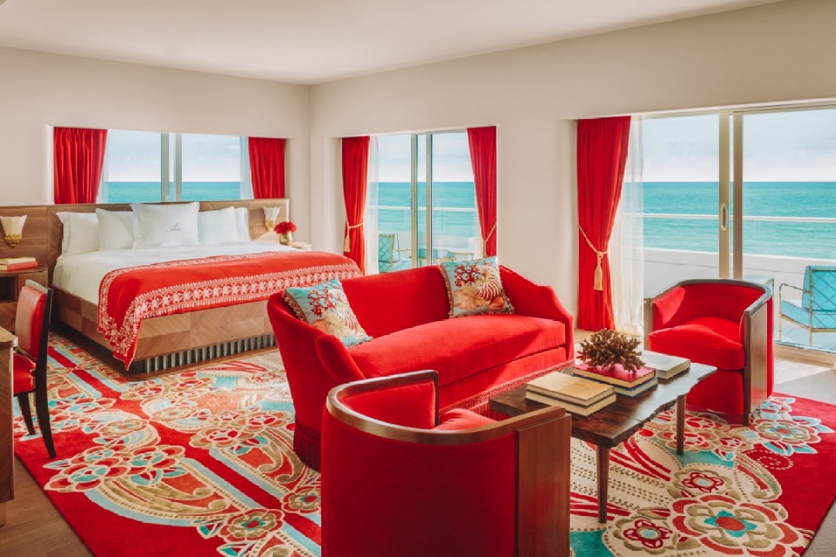 Spacious guest suite with red furnishings, patterned rug, and floor-to-ceiling ocean view windows
