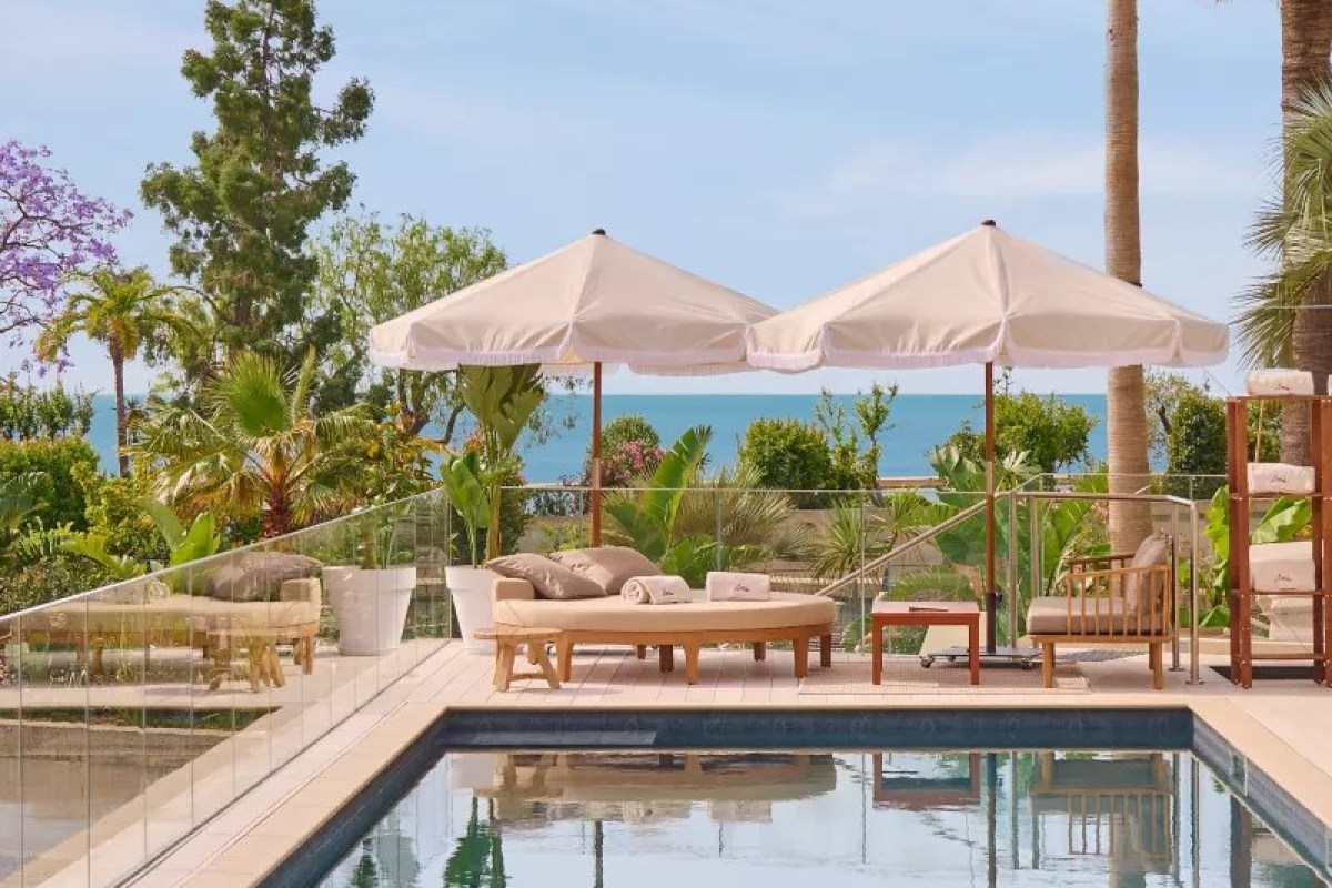 Poolside terrace with white umbrellas, loungers and sea view