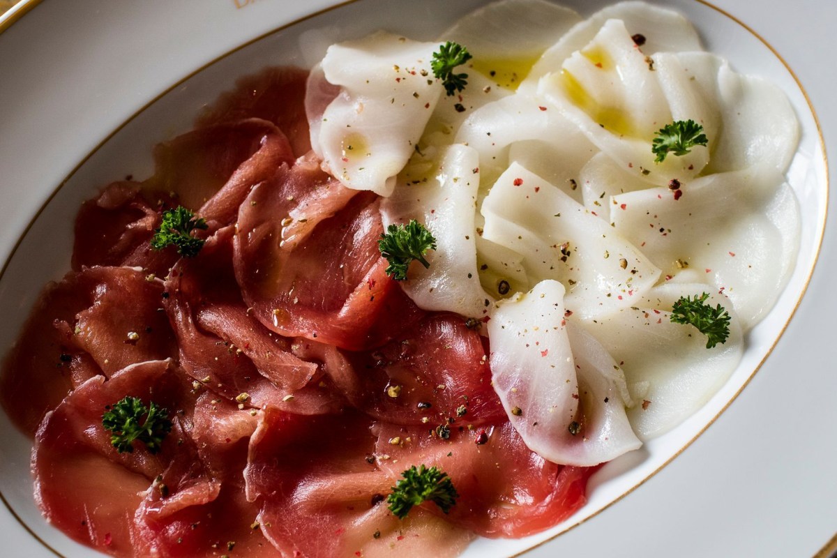 Plate of thinly sliced cured meat and shaved fennel with herbs