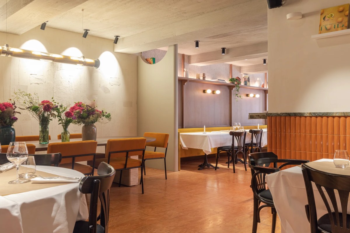 Interior view of the restaurant showing multiple dining nooks, orange tiled wall, banquette seating and table settings