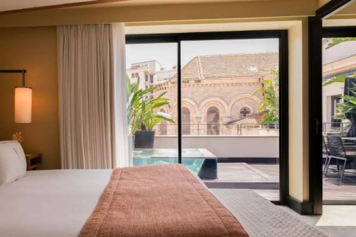 Hotel suite bedroom with plunge pool and terrace visible through window