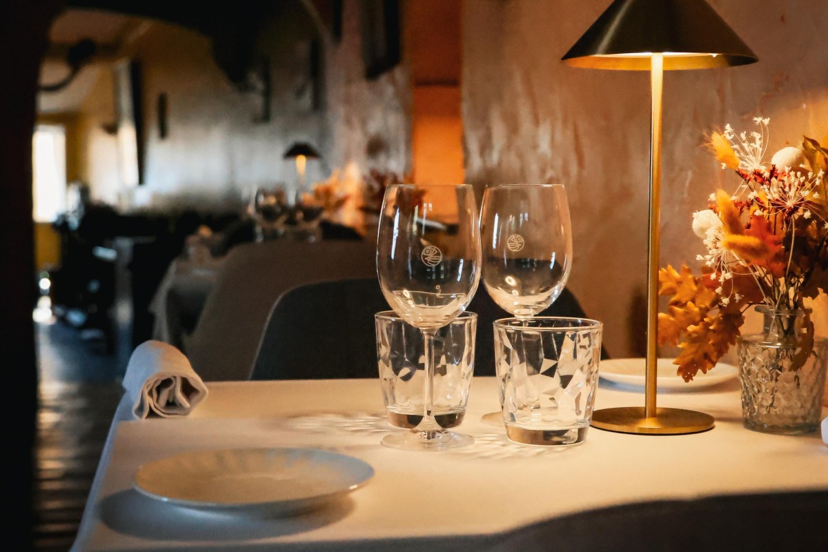 Elegant dining room with set tables, wine glasses, candle lamp, flowers, view down the restaurant