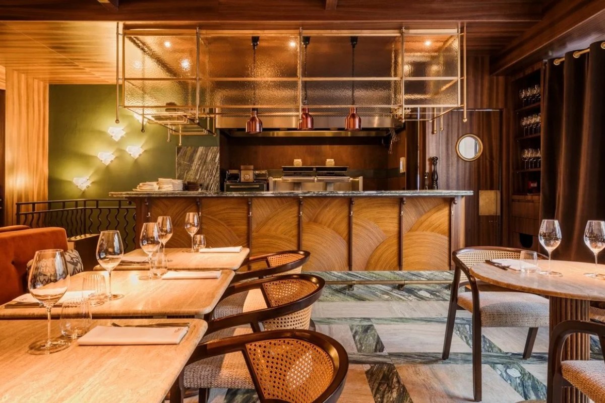 Elegant wood-paneled dining room with marble floor, bar and open kitchen pass visible