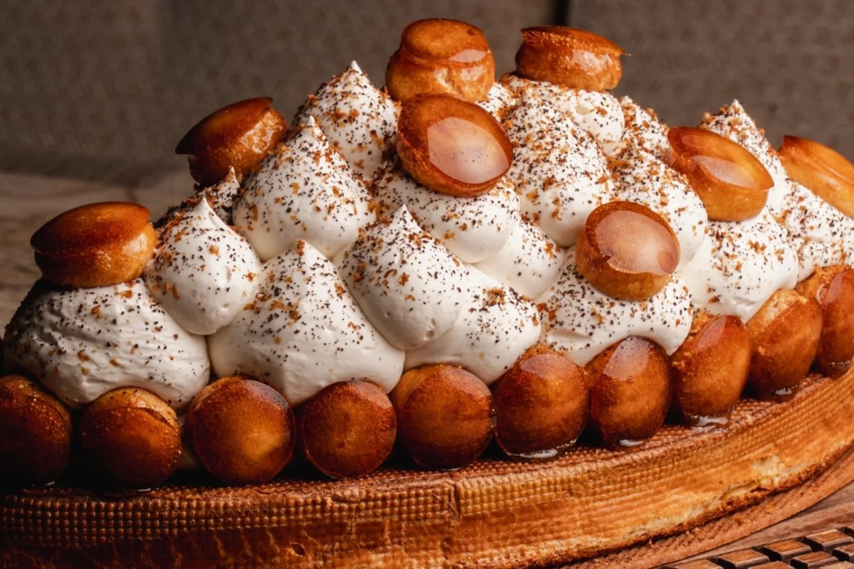 Saint-Honoré style pastry with caramelized choux puffs and whipped cream on a plate