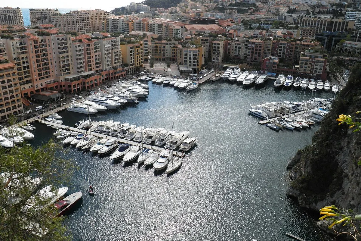 Port de Fontvieille in Monaco seen from the cliff, with boats in the marina and salmon-pink residential buildings around the harbour