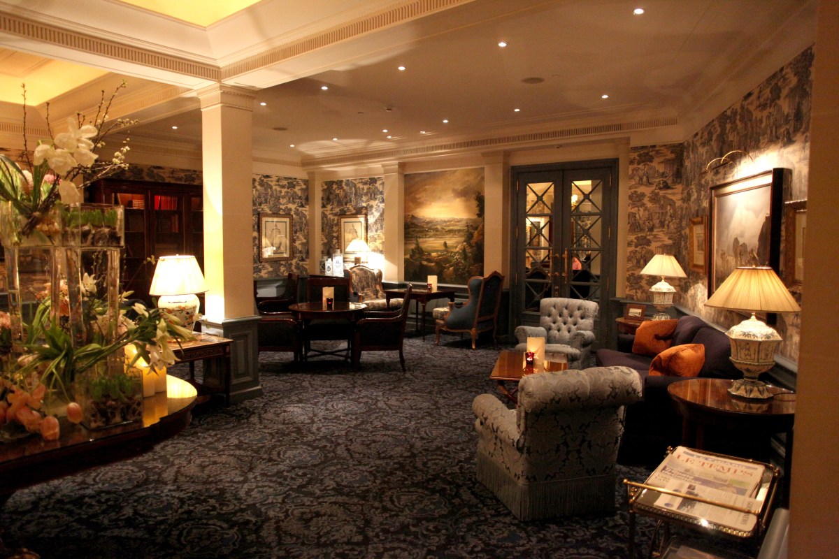 Elegant hotel lounge with toile wallpaper, antique furniture and soft lighting