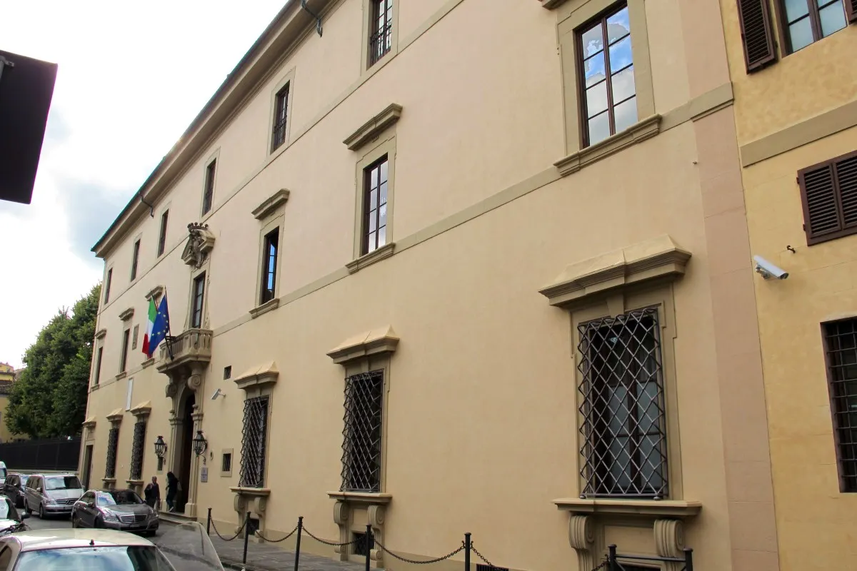 Wide view of the sand-colored Renaissance palazzo façade with shuttered windows, balcony and entrance, Florence hotel exterior