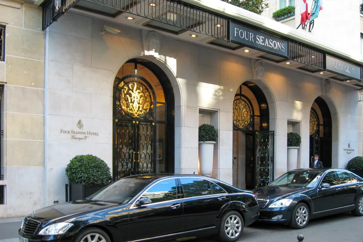Front facade entrance of Four Seasons Hotel George V with arched doorways and luxury cars parked outside